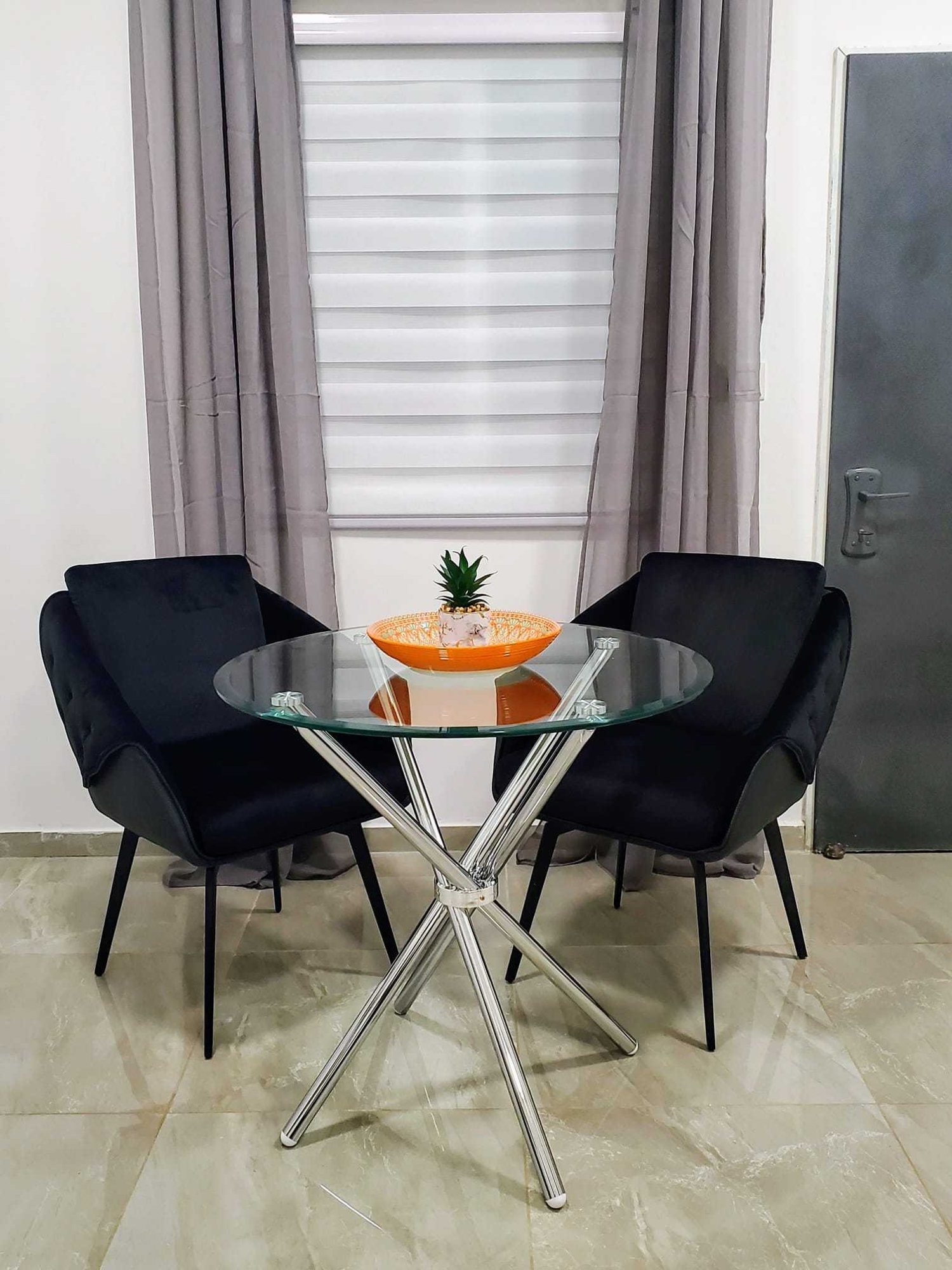Glass bistro table with two black velvet chairs by the window